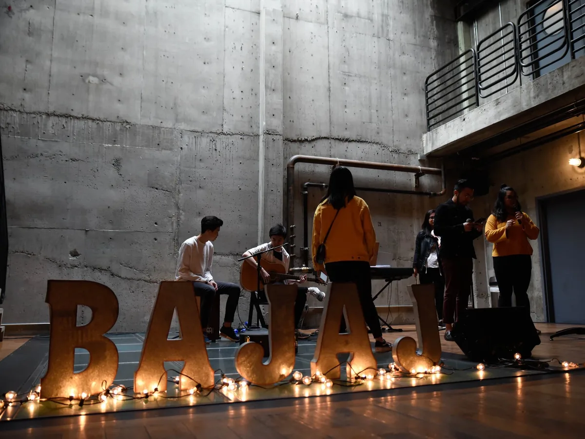 Musicians performing behind the glowing BAJAJ letters on stage