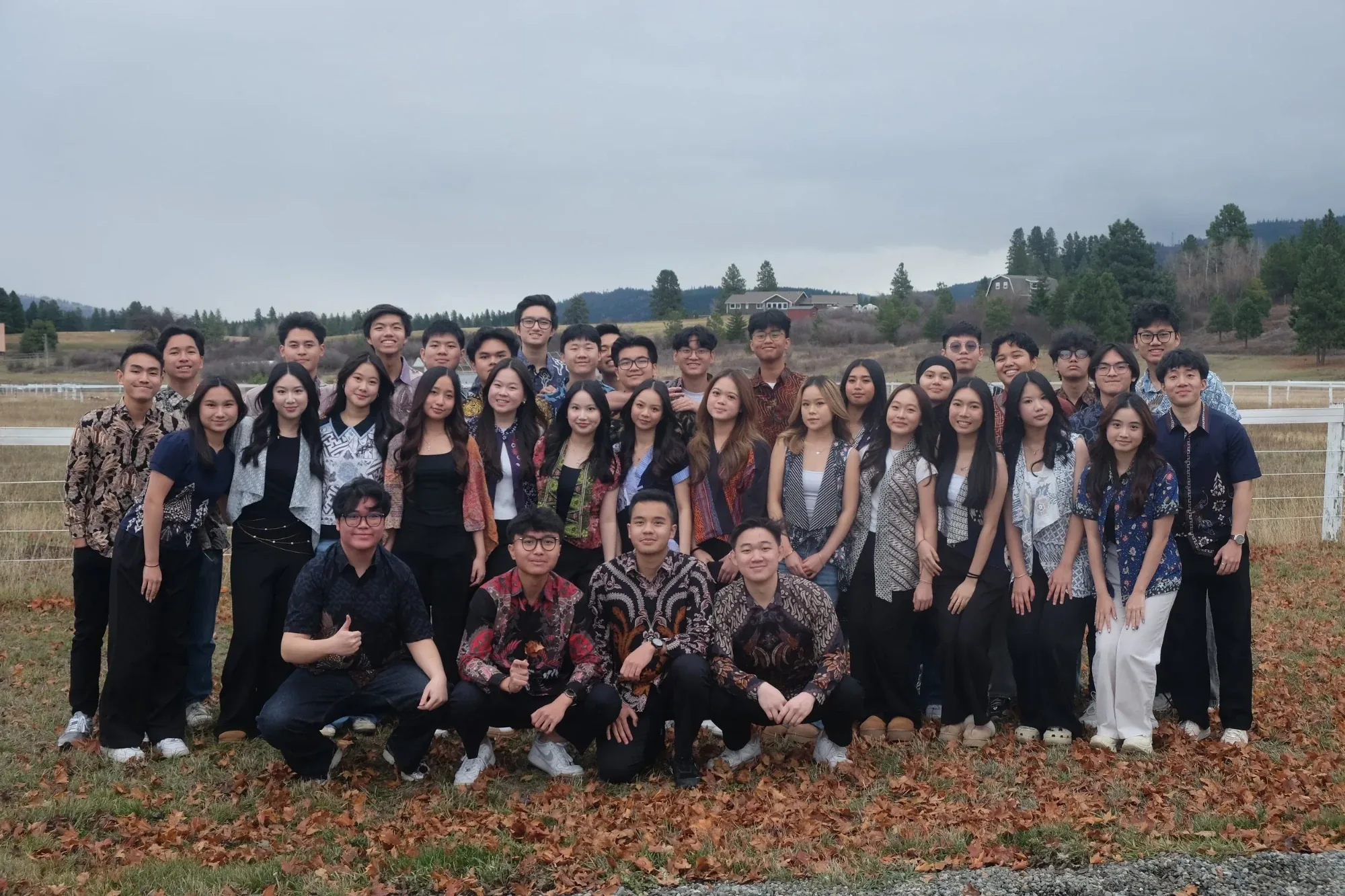 PERMIAS Seattle members in batik posing together in a field with pine-covered hills behind them
